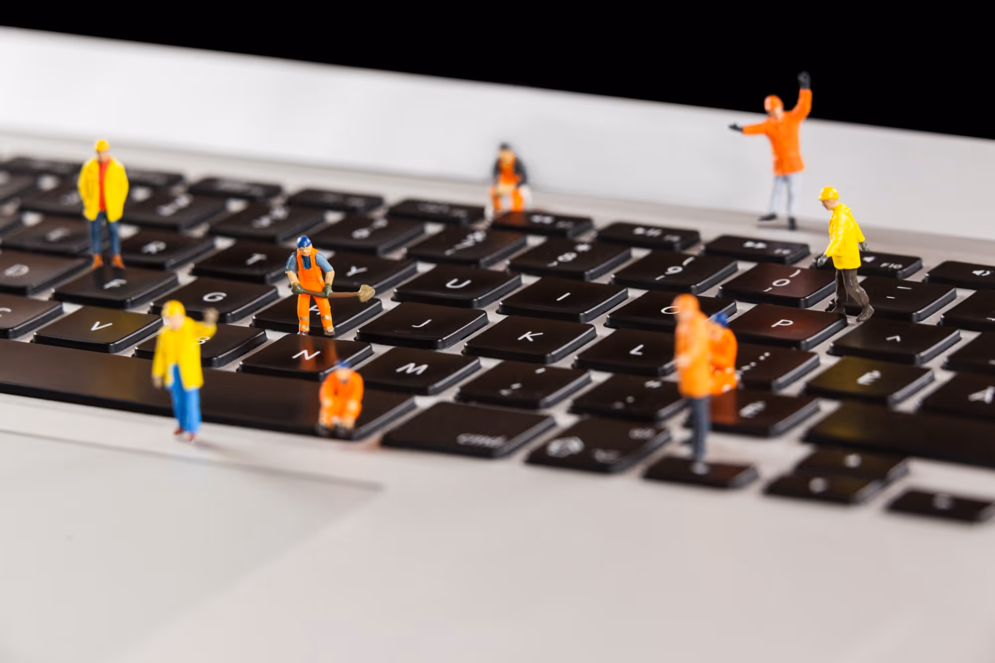 Miniaturfiguren auf einer Laptop-Tastatur als Symbolbild für Support und Pflege